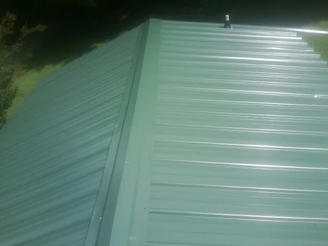 New green metal panels meeting at the ridge of a roof — Flat Roof Repair work by our crew in Spearfish