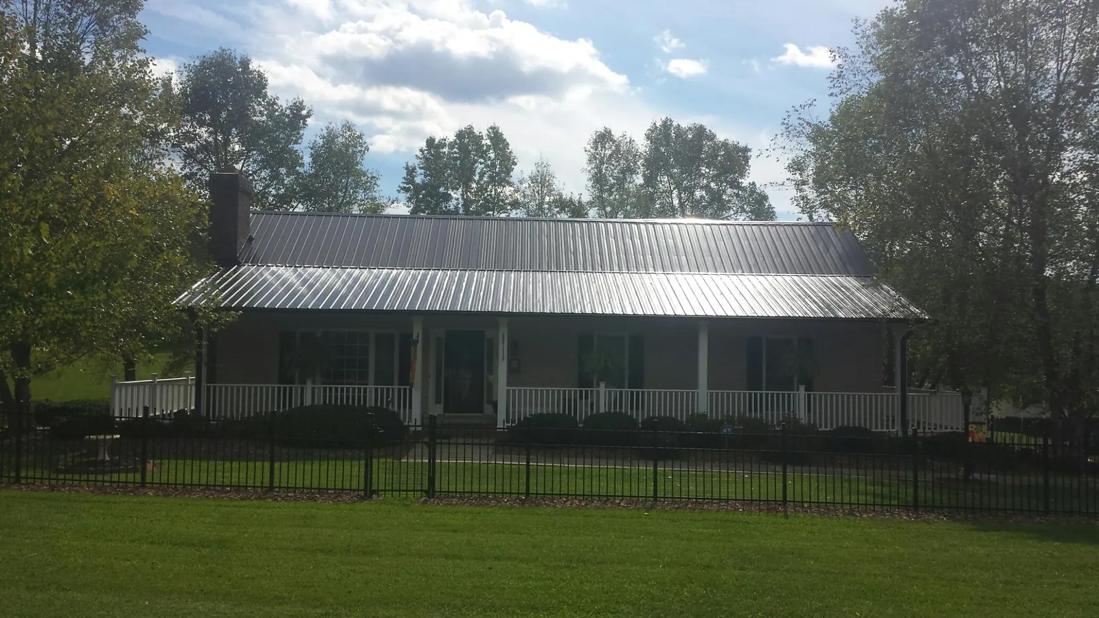 Gray metal roof on a brick ranch with a full width front porch — Gutter Guard Installation work by our crew in Spearfish