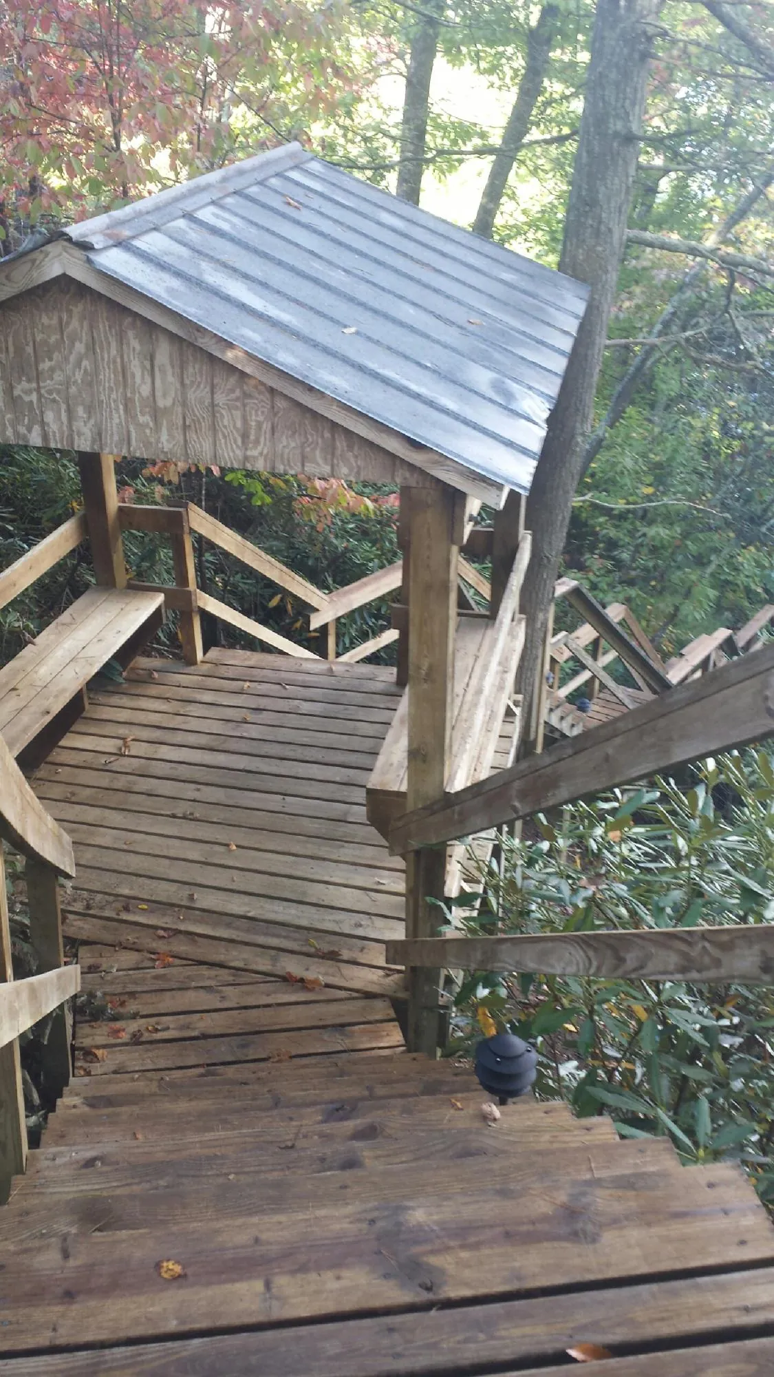 Metal roofed shelter over wooden steps on a wooded walkway — Skylight Repair & Installation work by our crew in Spearfish
