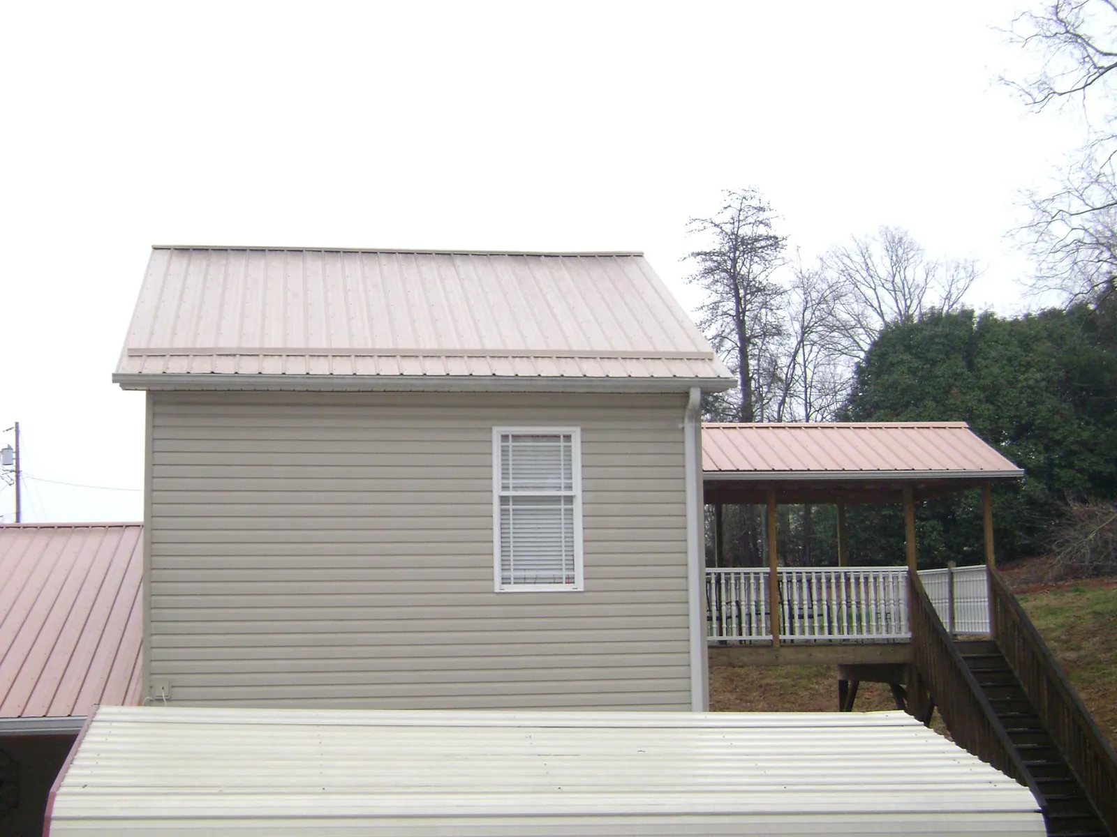 Tan metal roofs on a two story addition and attached porch, from a Roof Replacement job in Spearfish